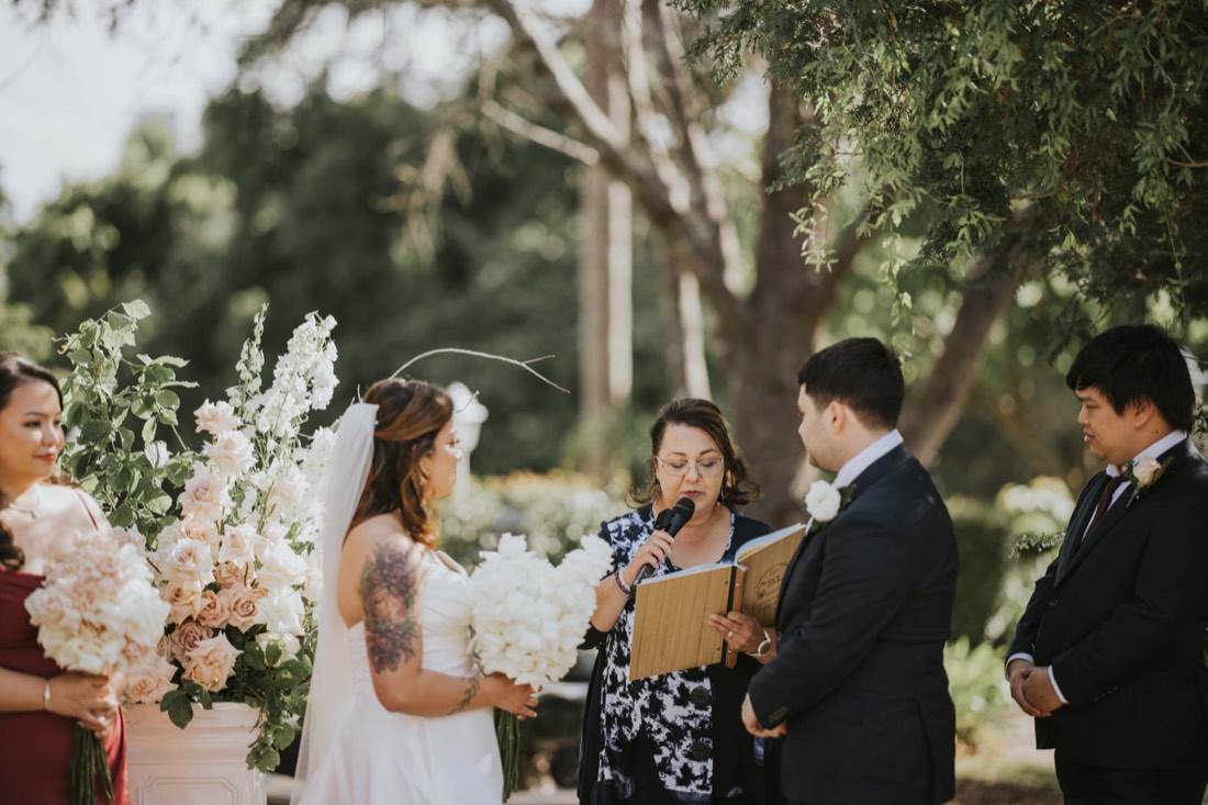 Josephine holding a wedding ceremony beside tall white and blush floral arrangements
