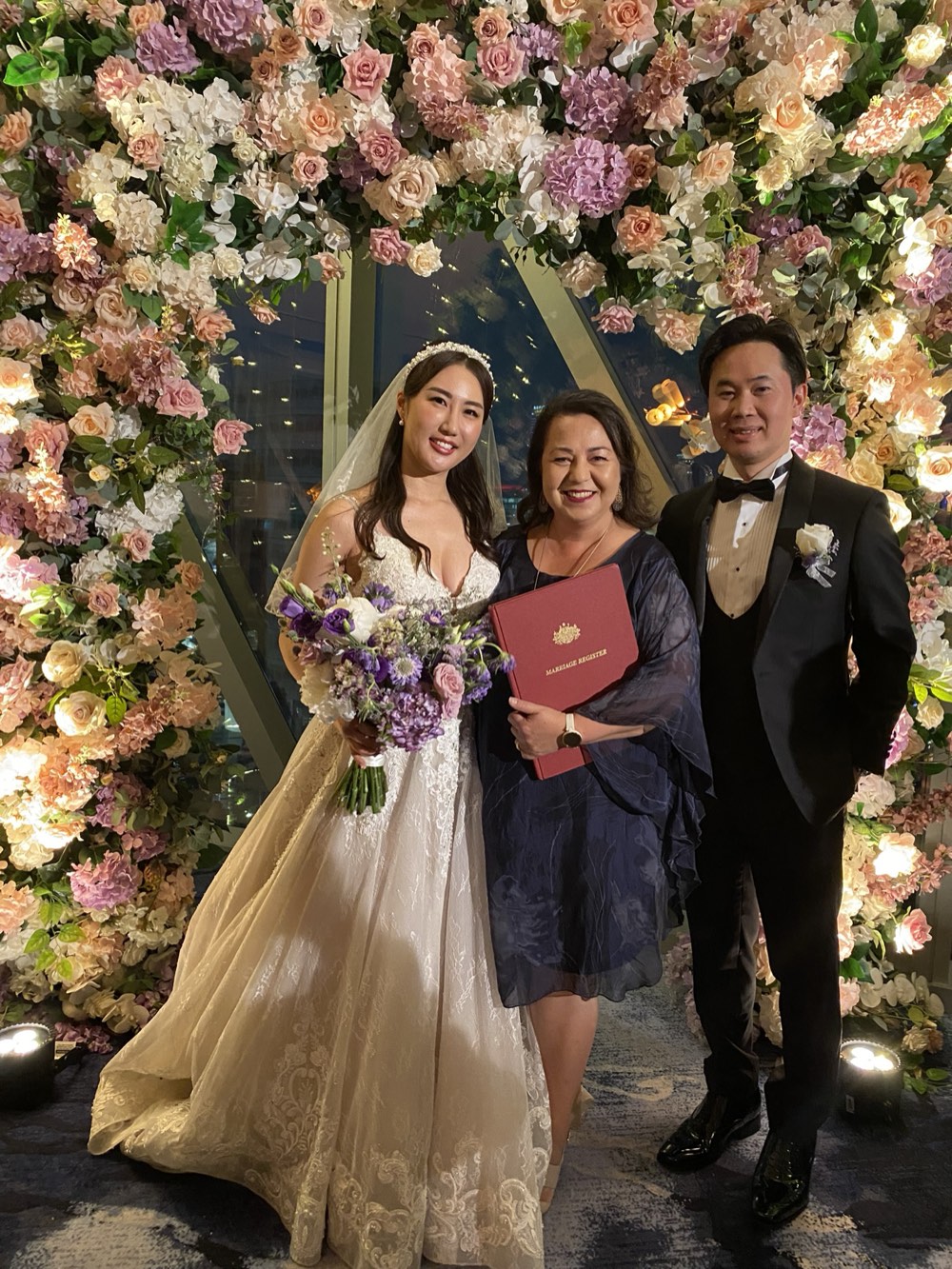Josephine with a married couple in front of a large floral installation