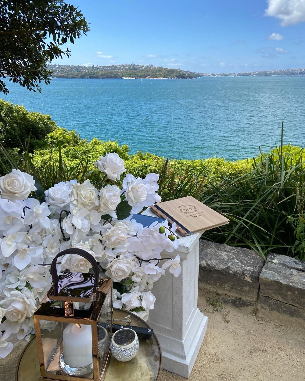 White roses beside the marriage register on a signing table overlooking the water