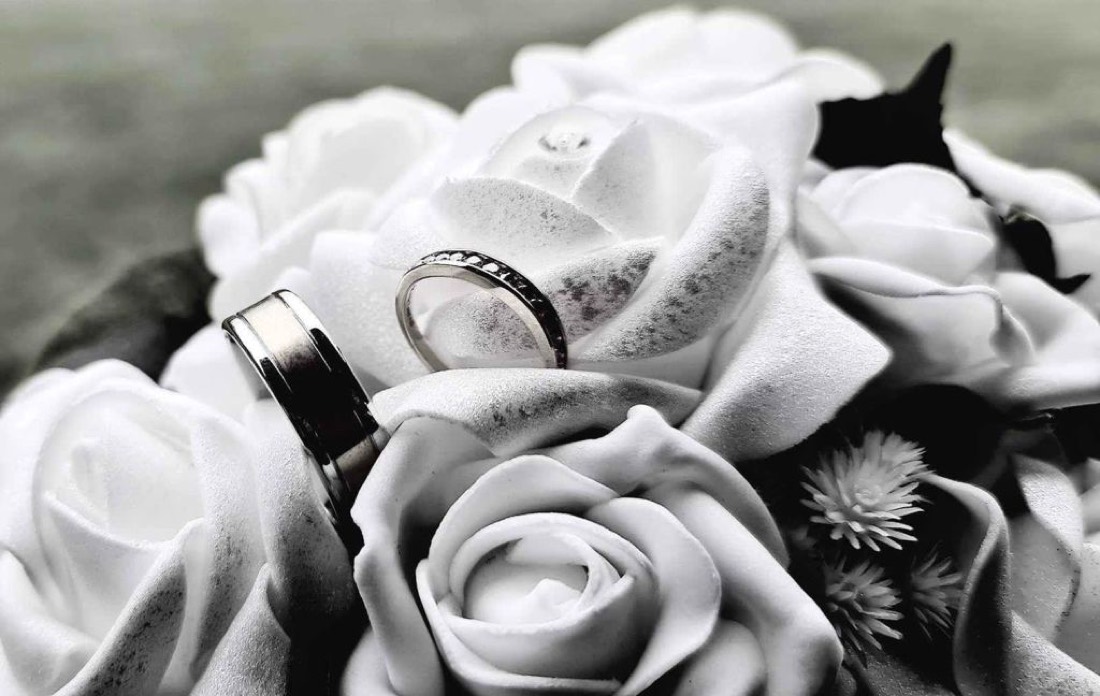 Two rings resting among white roses